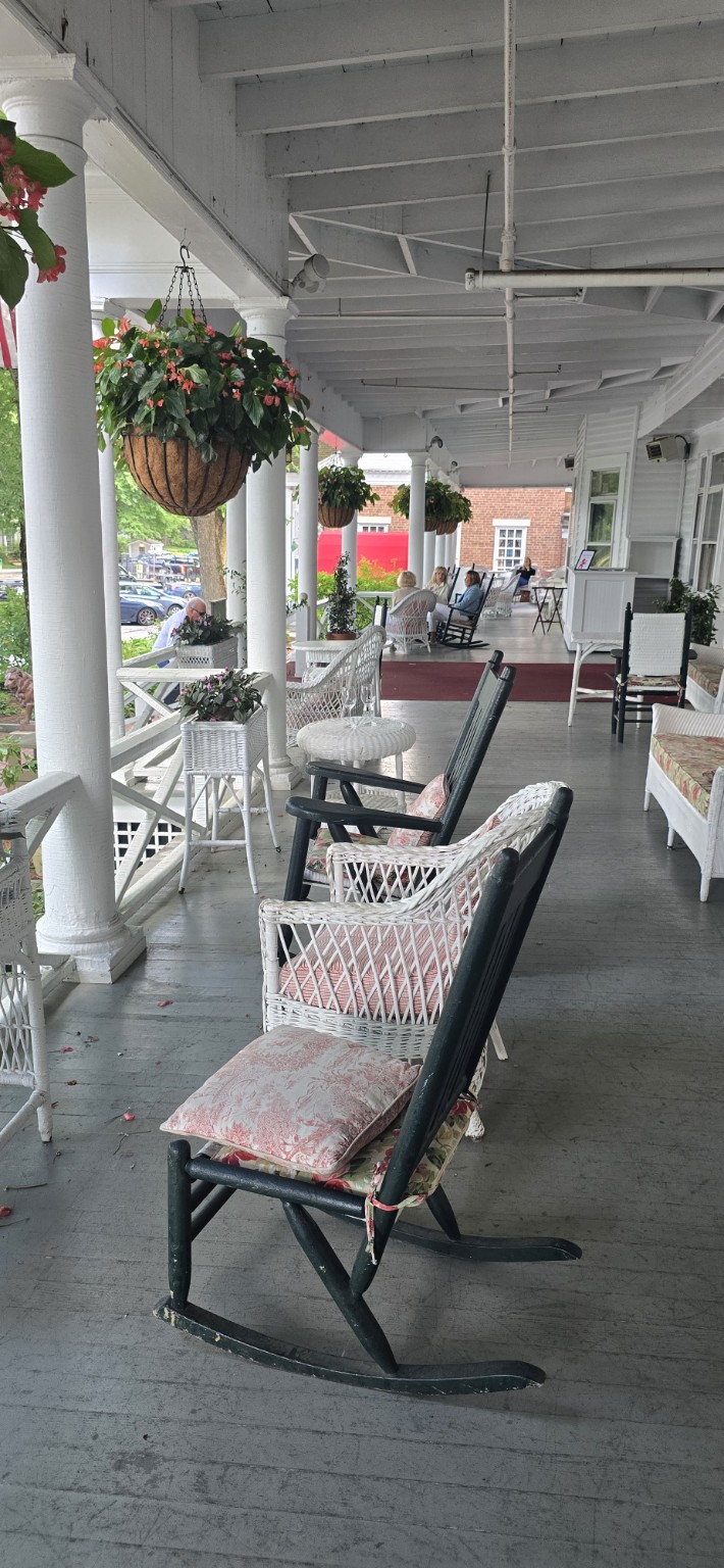 A group of elderly people lounging on a wide porch.